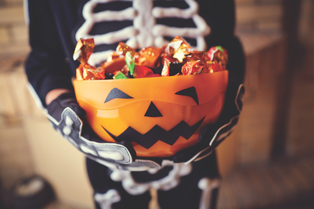 Boy in skeleton costume holding bowl full of candies