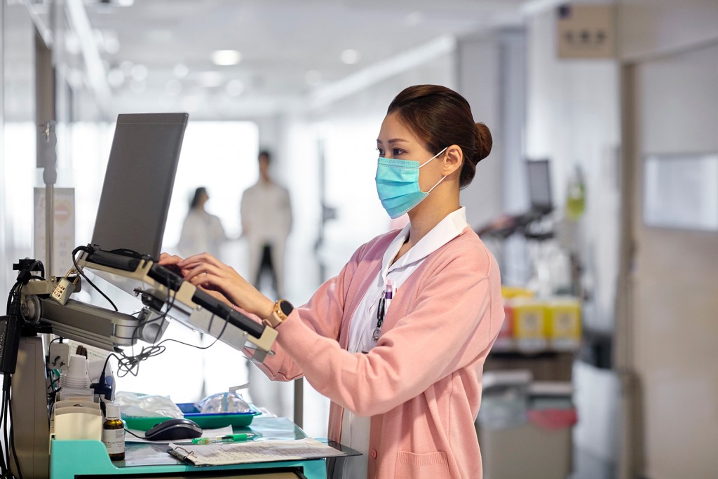 Nurse Using Laptop While Working On Medical Report