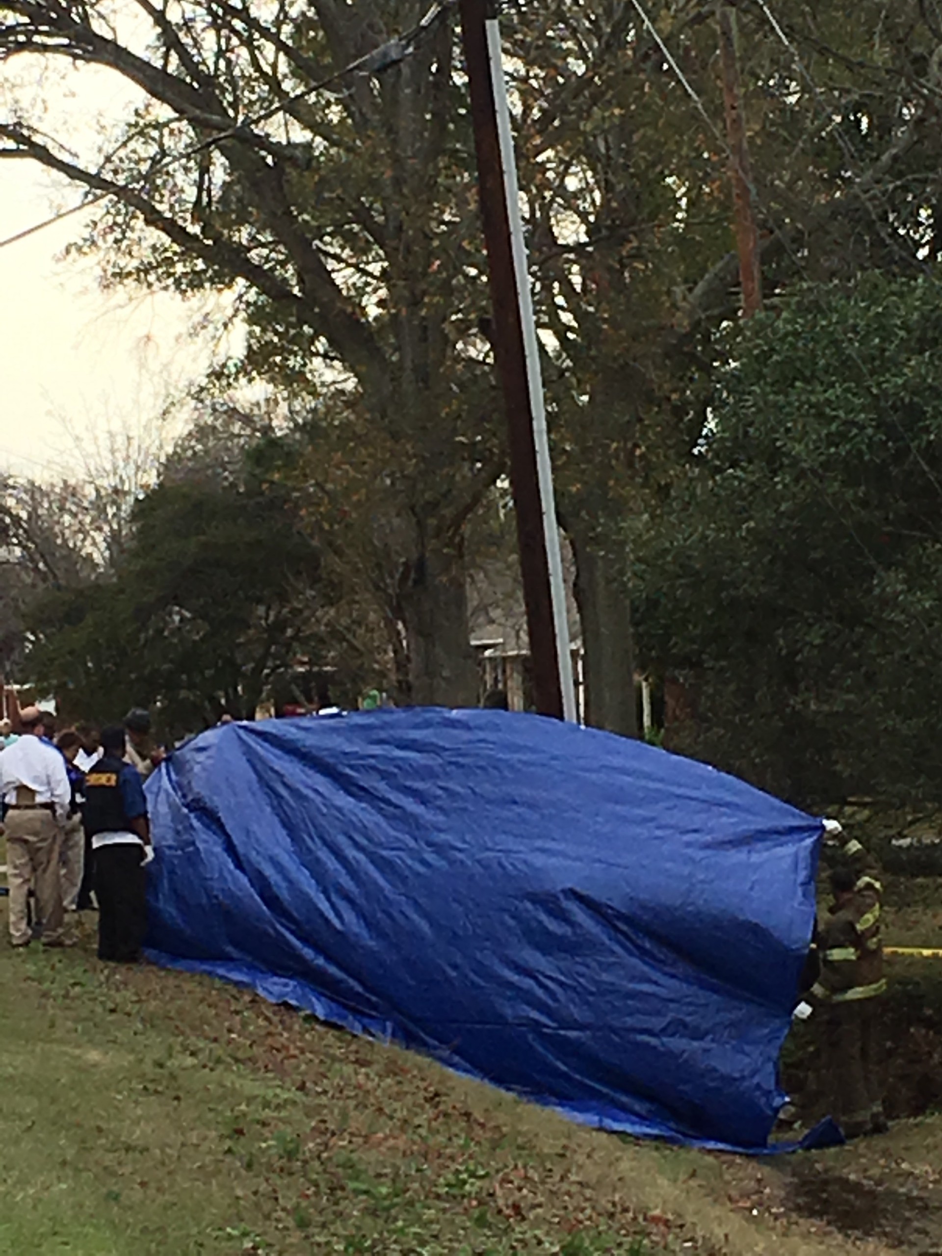 The body was carried under a blue tarp while deputies investigate.