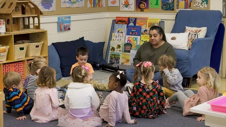 Smiling child care teacher reading to toddlers