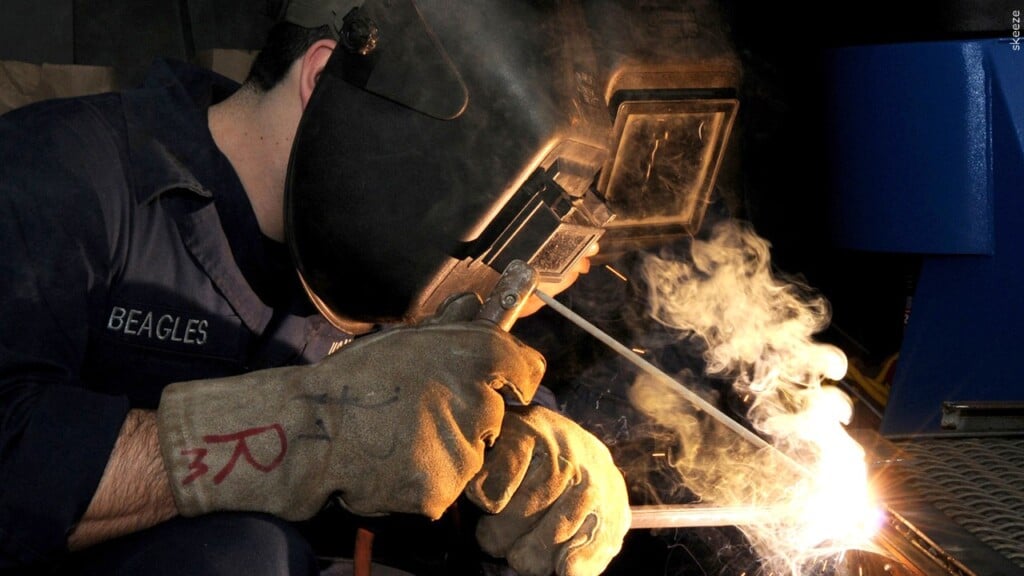 Stock image of a worker welding metal inside an industrial manufacturing facility