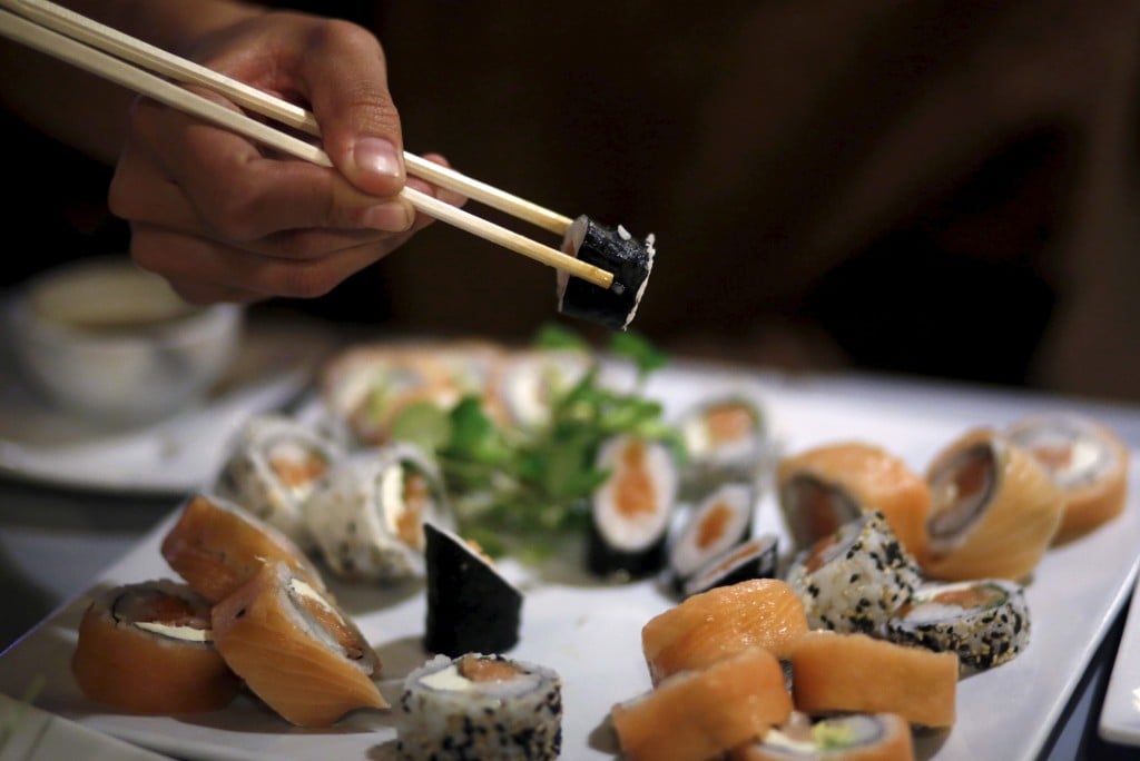 A Woman Uses Chopsticks To Eat Sushi At A Restaurant In La Serena, Chile
