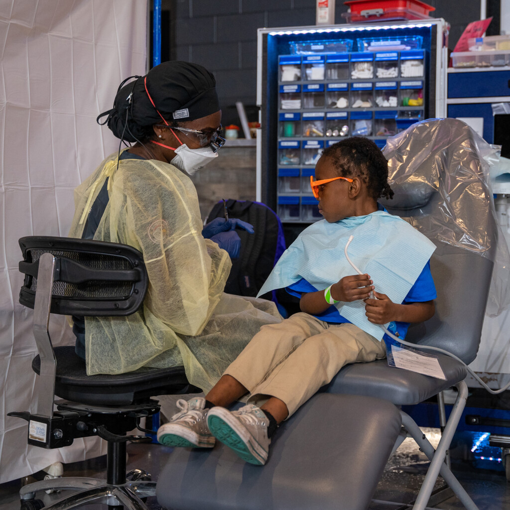 Child sitting in dental care getting care from a dentiist or dental hygienist