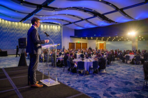 Walt Farrell from AT&T on stage at the 2023 Most Influential Georgians event in a blue ballroom with a wavy blue ceiling at the Georgia Aquarium in Atlanta