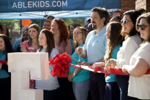 Close up of a ribbon cutting with a gorup of people