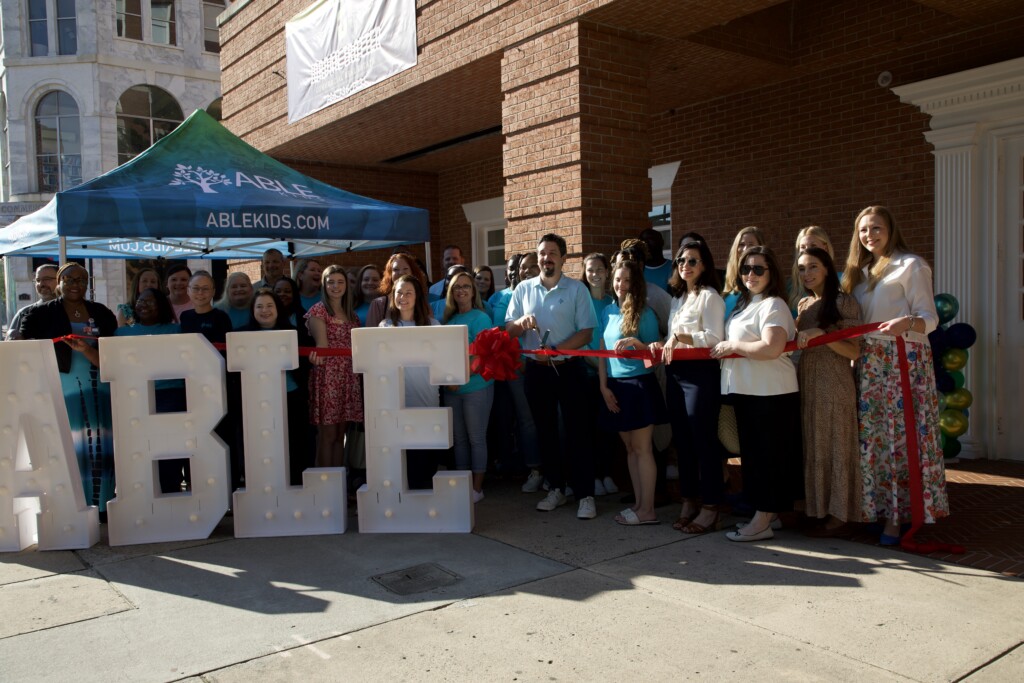 Outside of building ibbon cutting with a gorup of people