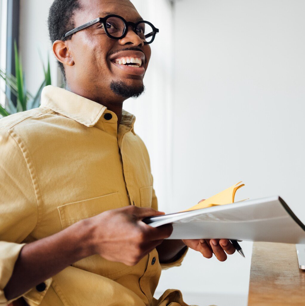Man With Yellow Shirt Smiling Holding Paper