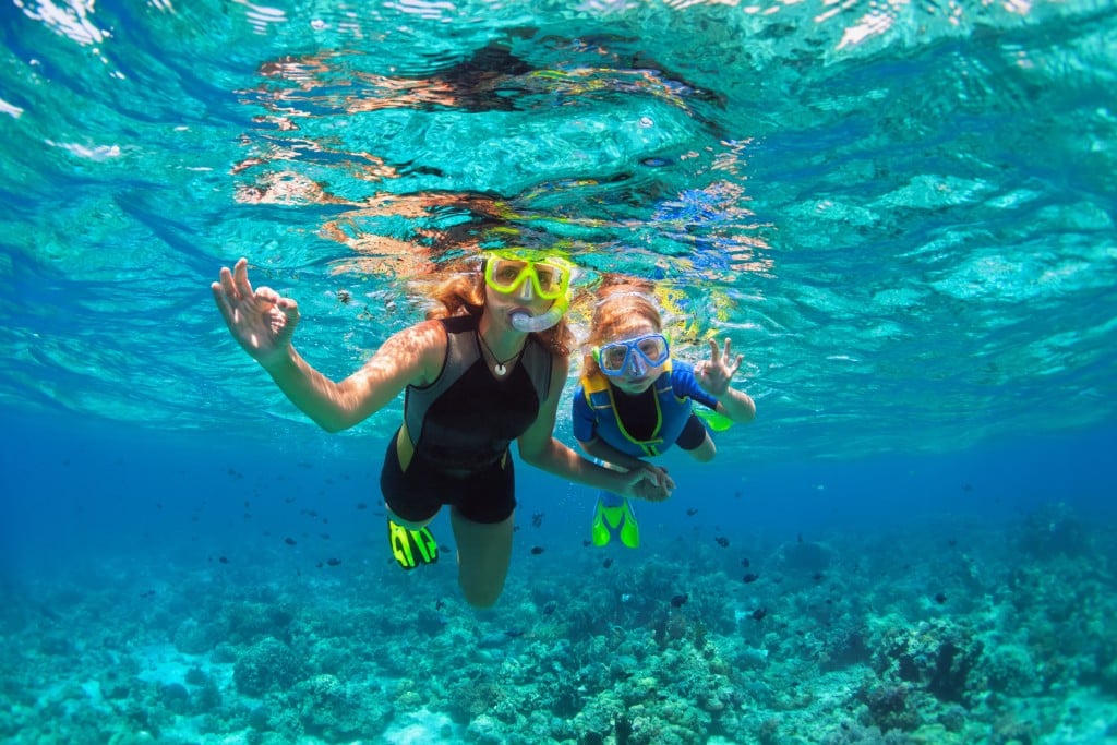 Mother, Kid In Snorkeling Mask Dive Underwater With Tropical Fishes