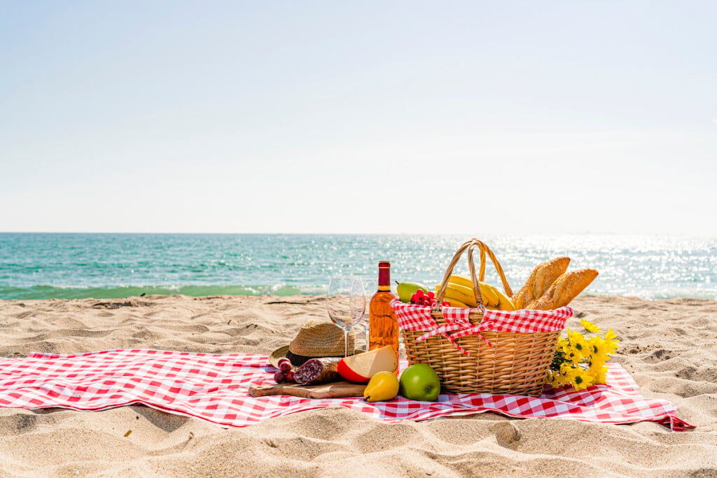 Wicker Picnic Basket With Food And Wine By The Beach