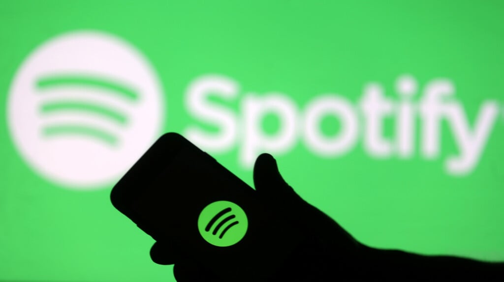 A Smartphone Is Seen In Front Of A Screen Projection Of Spotify Logo, In This Picture Illustration