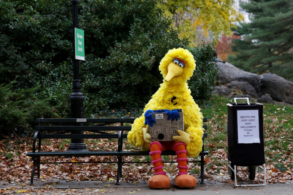 A Man Dressed As The Sesame Street Character Big Bird Sits On A Bench Waiting To Take Pictures With People Walking Through Central Park In New York