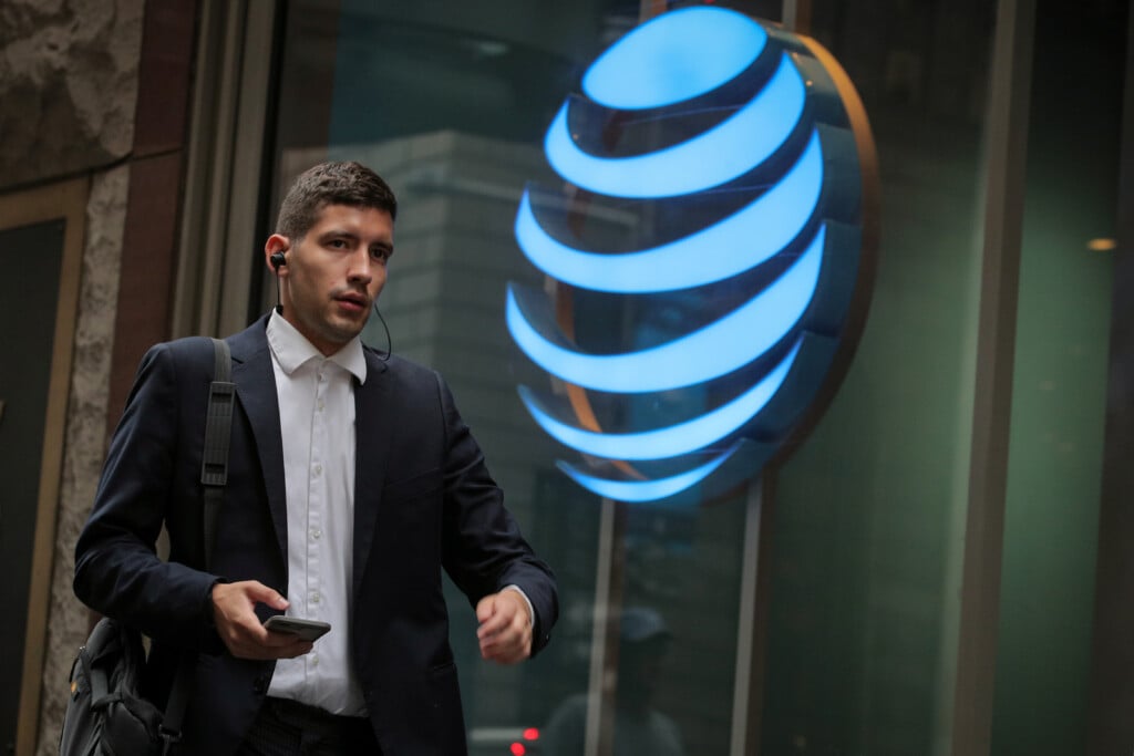 A Man Uses His Phone As He Passes By An At&t Store On Wall St. In New York
