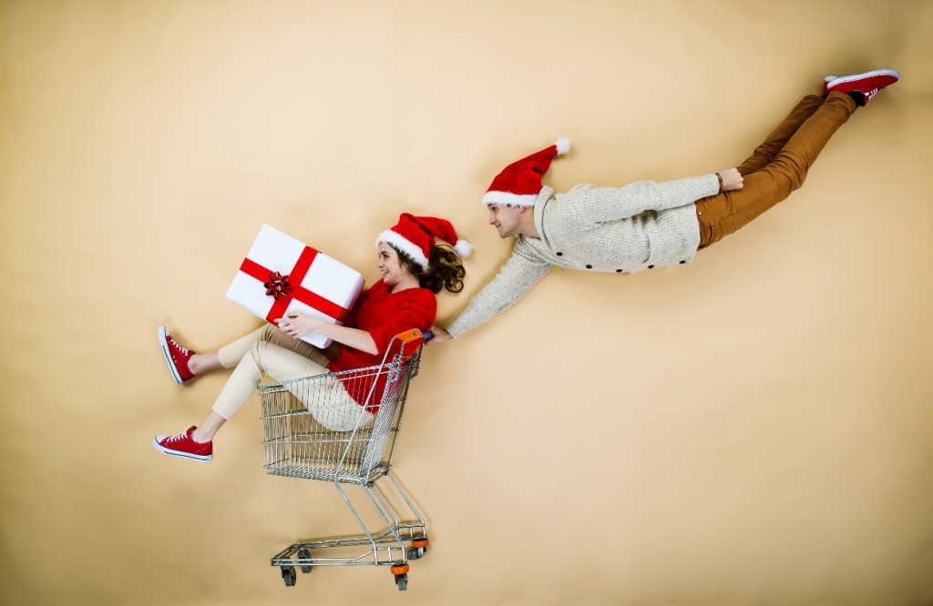 young couple in Christmas hats having fun running with shopping cart (Source: Storyblocks)