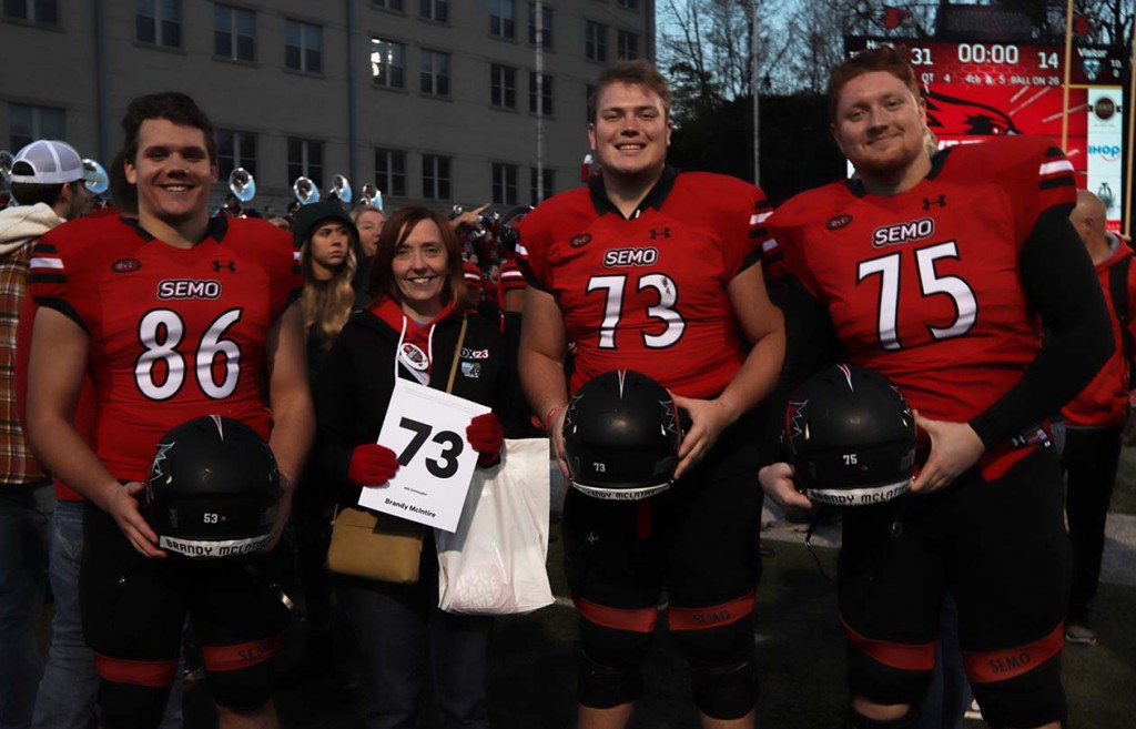 Brandy McIntire poses with three SEMO football players who played with her name on their helmets Nov. 20.