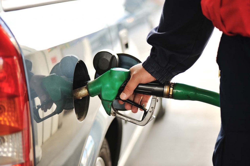 Close up image of a man's hand refilling the car with a gas pump