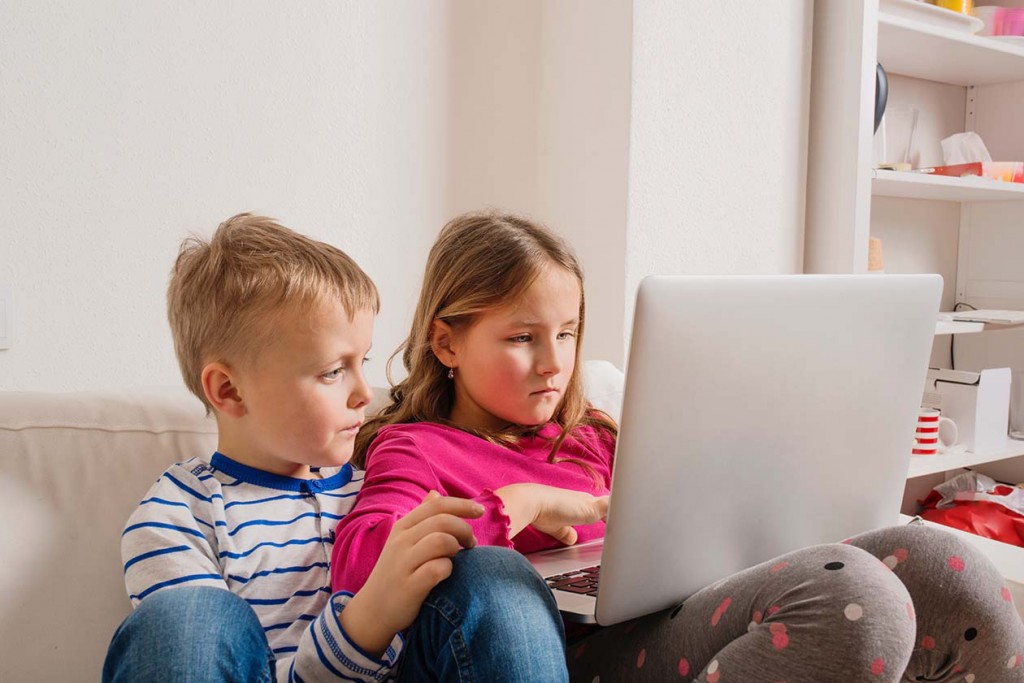 little girl and boy sitting on sofa with a laptop computer at home (Source: Storyblocks)