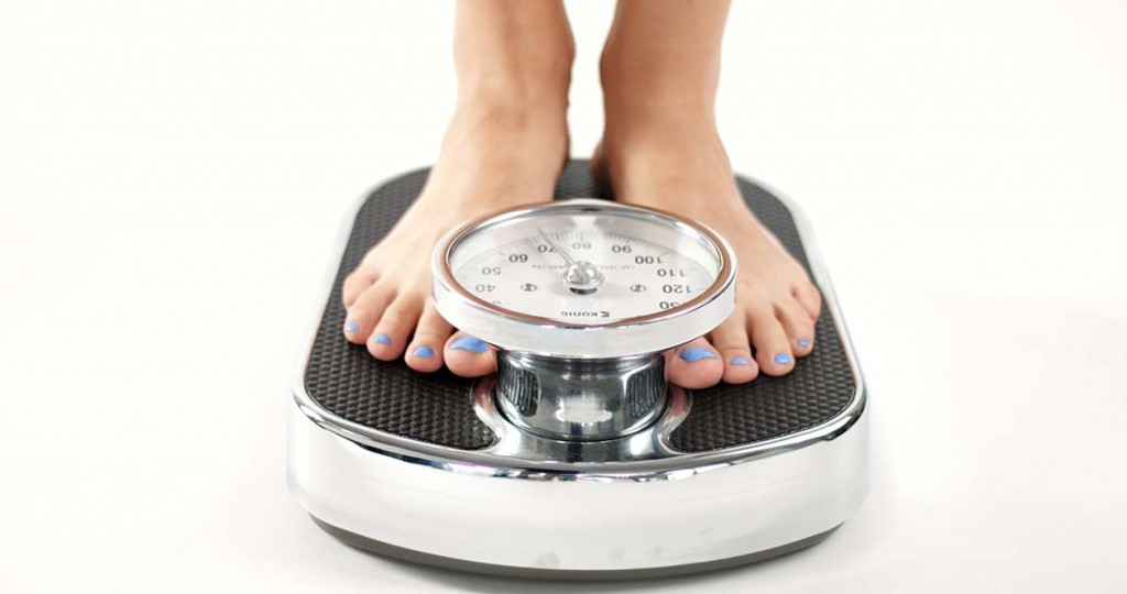 woman's feet with blue toenails stepping on scale weight (Source: Storyblocks)
