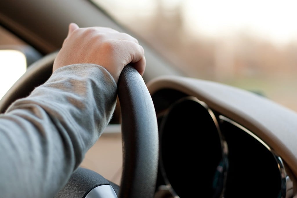 woman holding the steering wheel of a car with one hand while driving (Source: Storyblocks)