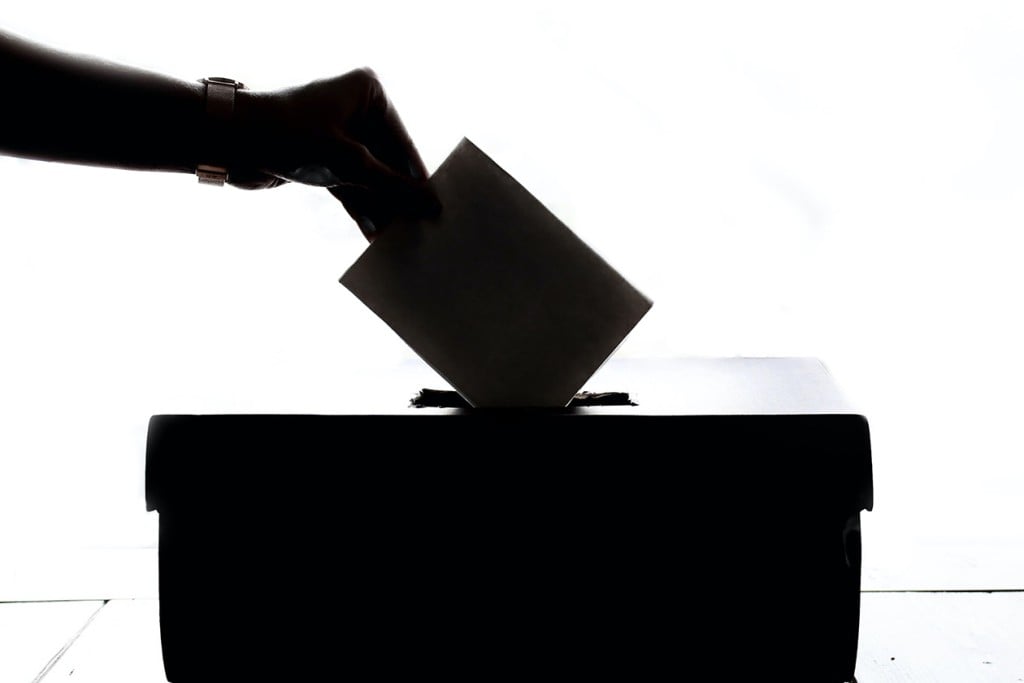 hand putting ballot in box (Source: Pexels)