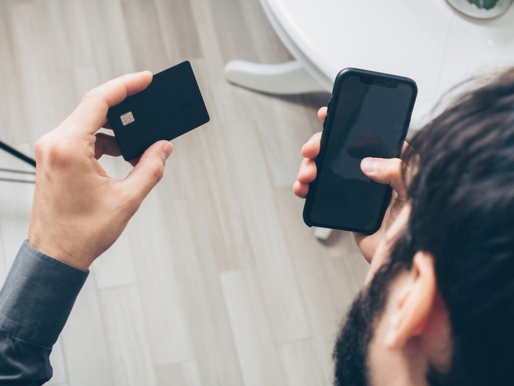man holding credit card and phone (Source: Pexels/Mikhail Nilov)