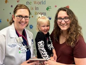 Julie A. Benard, MD, FAAP, DABOM, pediatrician with Cape Physician Associates, shares a book and a smile with Kirstan Mirgeaux and her daughter, Annie (Source: sfmc.net)