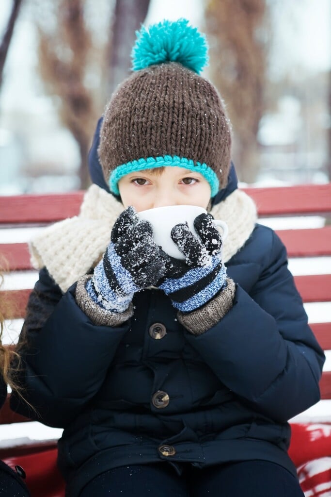 child in winter coat drinking hot beverage (Source: Pexels/Aleks)