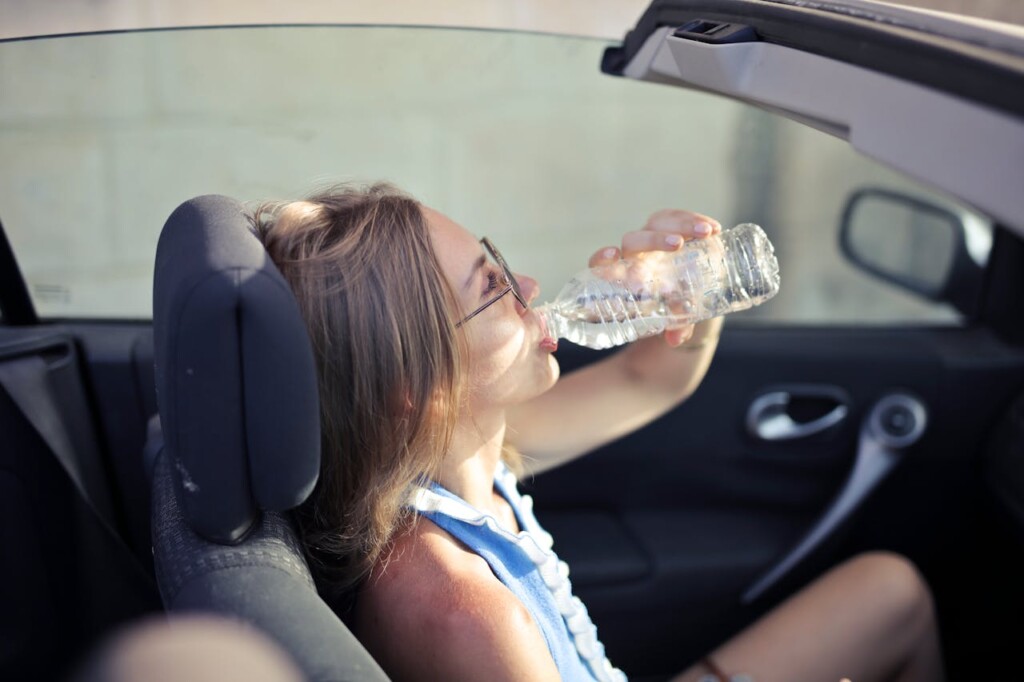 Woman drinking water in a convertible (Source Pexels/Andrea Piacquadio)