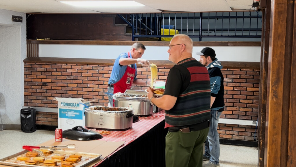 A man serves spaghetti to two men at the annual spaghetti day event