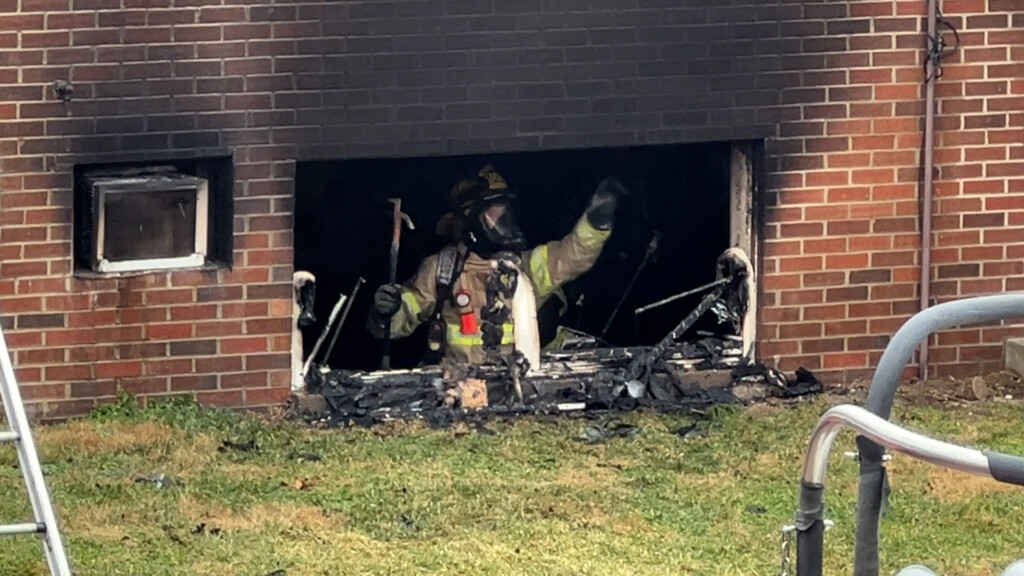 A firefighter is seen in a basement apartment through the open window where black smoke bellowed out.