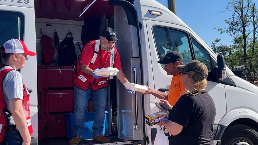 Red Cross volunteer hands out meals to tornado survivors