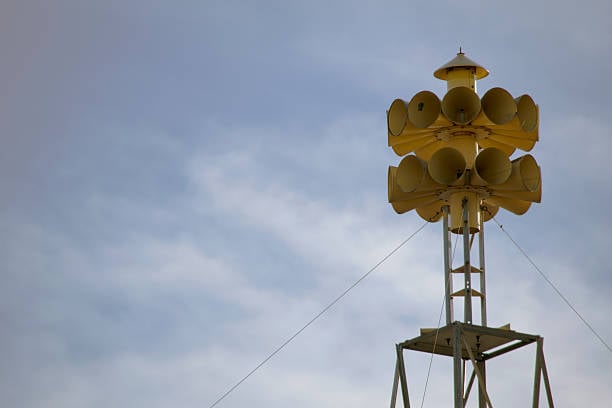 A Yellow Tornado Siren Waiting For Duty On A Building Roof