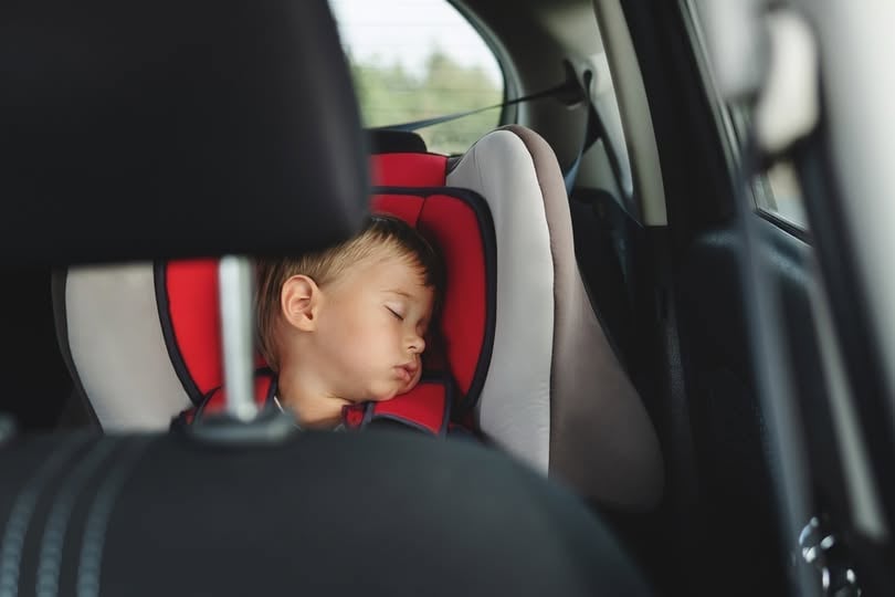 Adorable Boy Peacefully Sleeping In A Car Seat Inside A Vehicle.