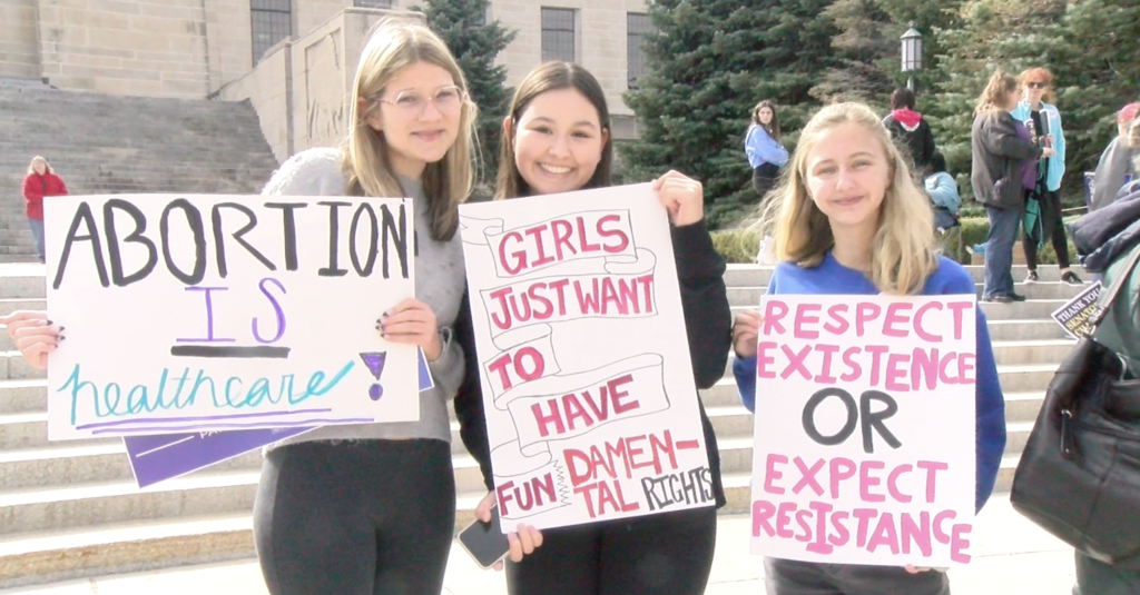 teens pose with reproductive rights signs
