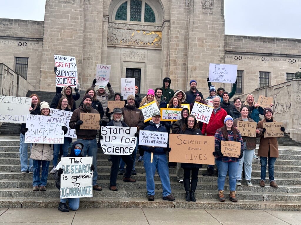Lincoln residents stand outside the capitol building as they stand with science.