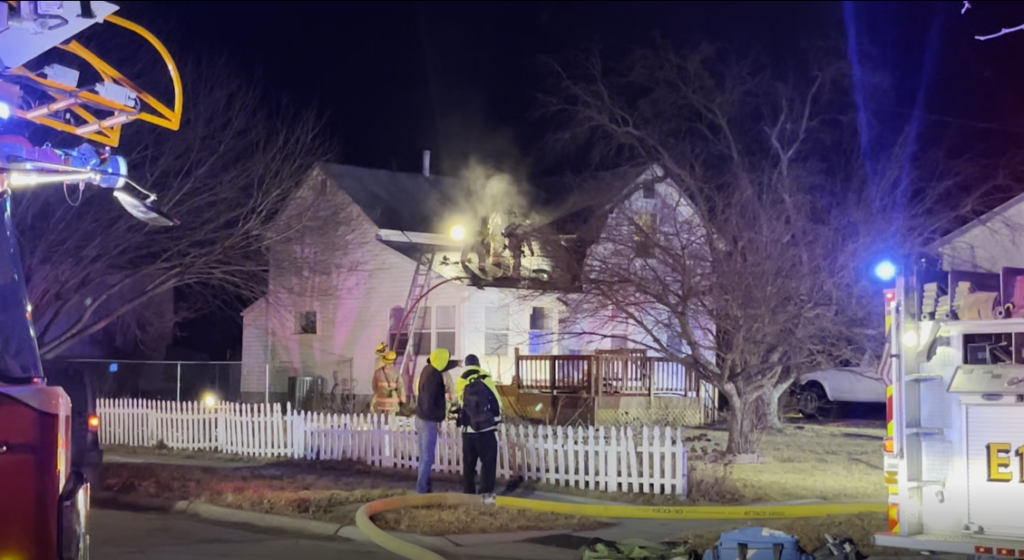 Firefighters stand on the roof of a Lincoln home as smoke rises during an overnight house fire near SW 9th Street and West A Street.