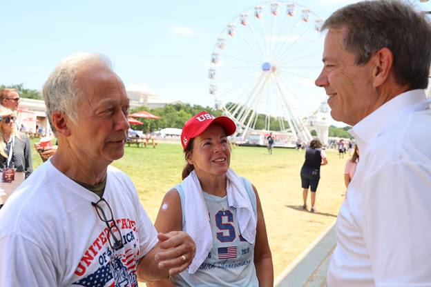 Jim Pillen welcoming two people to the Nebraska pavillion.