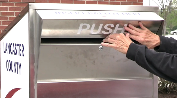 Voter pushes open metal voting drop box.