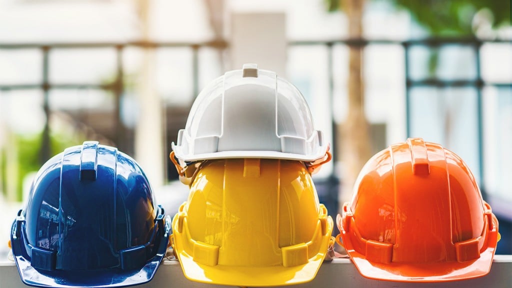 White, Yellow And Other Colored Safety Helmets For Workers' Safety Projects In The Position Of Engineers Or Workers On Concrete Walls In The City.