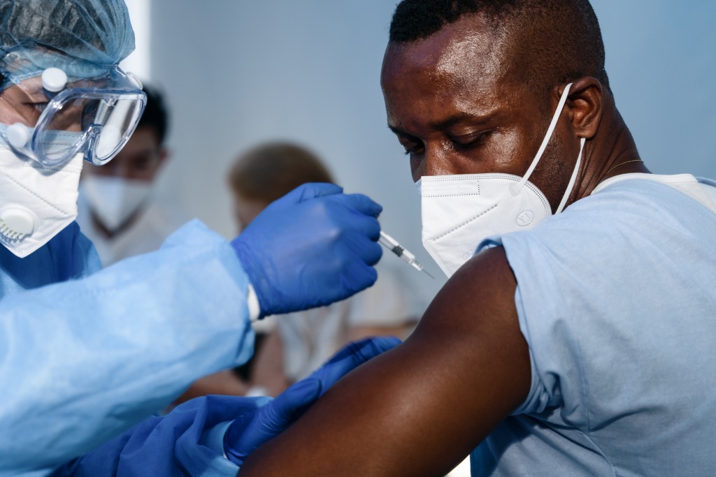 African Americam Man Looking At Coronavirus Covid 19 Syring When Medical Staff Injecting Vaccine To Arm Muscle To Build Immunization Of Coronavirus Covid 19 For Him