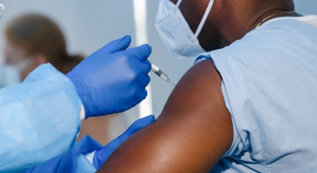 Hand Of Medical Staff In Blue Glove Injecting Coronavirus Covid 19 Vaccine In Vaccine Syringe To Arm Muscle Of African American Man For Coronavirus Covid 19 Immunization