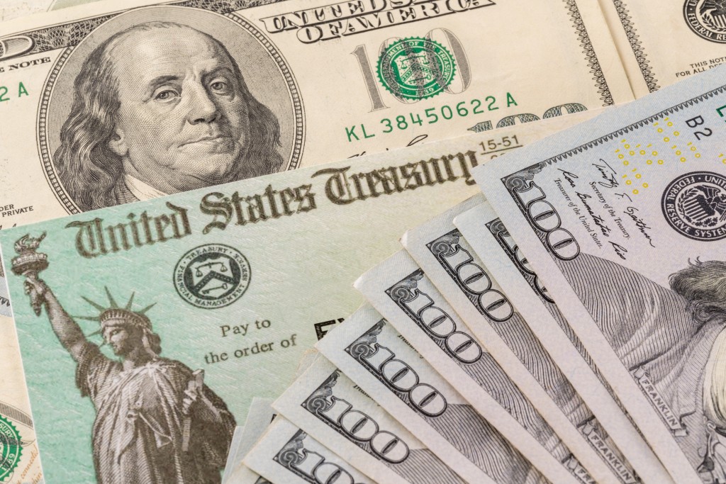 Illustration Of The Federal Stimulus Payment Check With Stack Of Cash Surrounding Payment