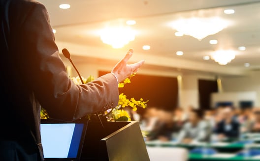 Business Man Making A Speech In Front Of Audience At Conference Hall.