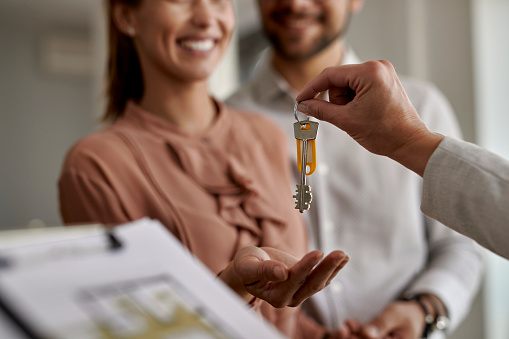 Close Up Of Real Estate Agent Giving New House Keys To A Couple.