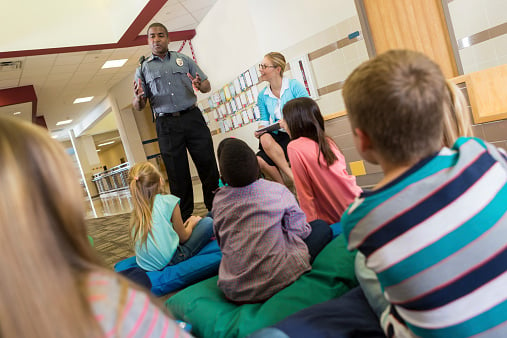 Police Or School Security Officer Speaking To Young Students.
