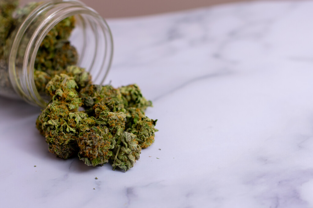 A Glass Jar With Colorful Cannabis Nugs Pouring Out Of It