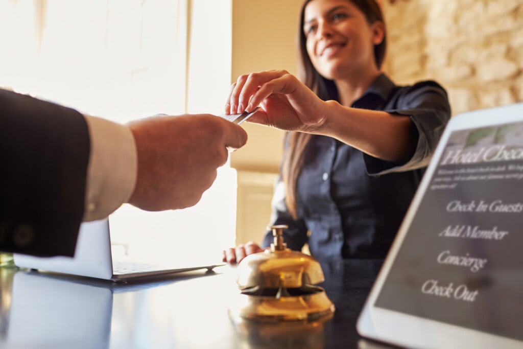 Guest Takes Room Key Card At Check In Desk Of Hotel