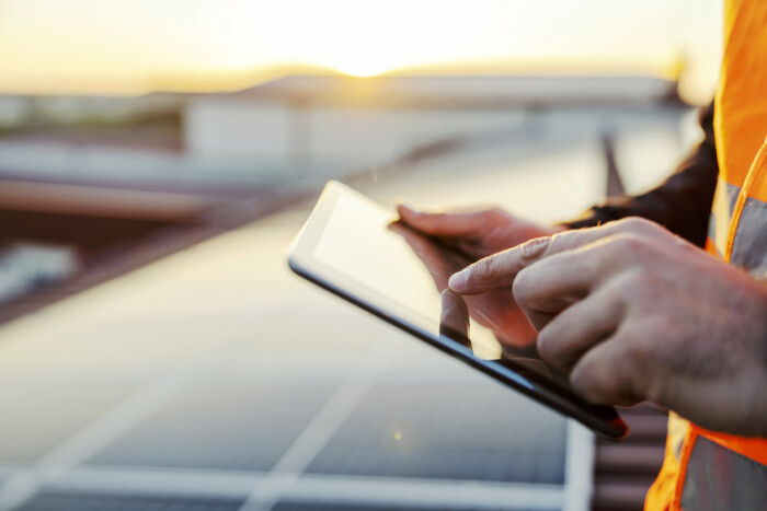 Close Up Of Hand Scrolling On Tablet And Checking On Solar Panels.