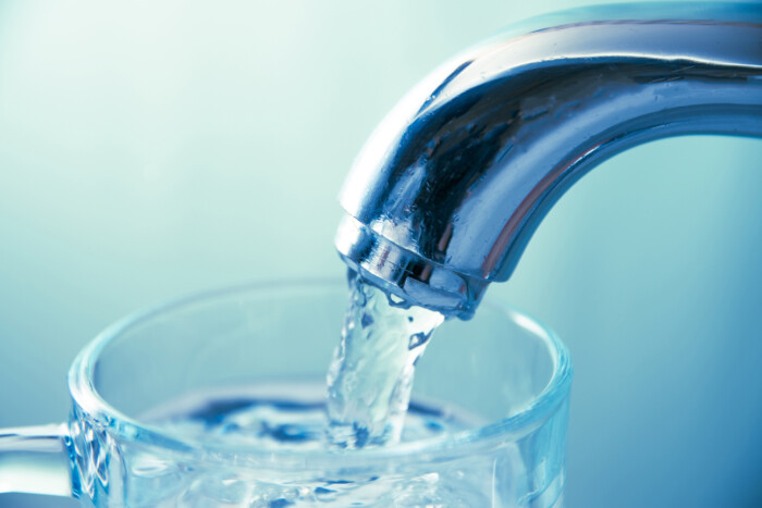 Close Up View Of Water Flowing From Tap Into Glass
