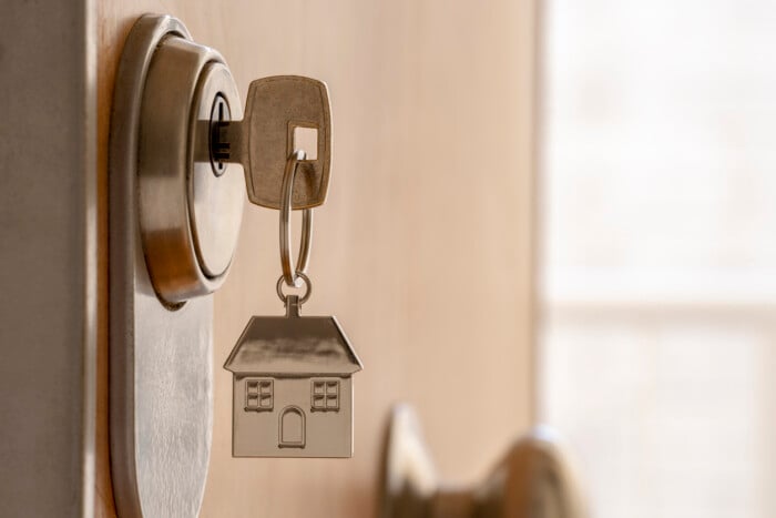 Close Up Of Key And House Keychain ​​in High Security Door Lock. Home Insurance Concept. Copy Space.