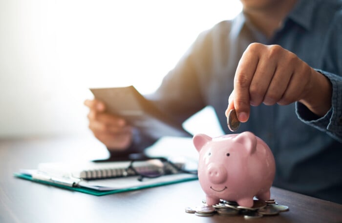 Close Up Image Of Man Hand Putting Coins In Pink Piggy Bank For